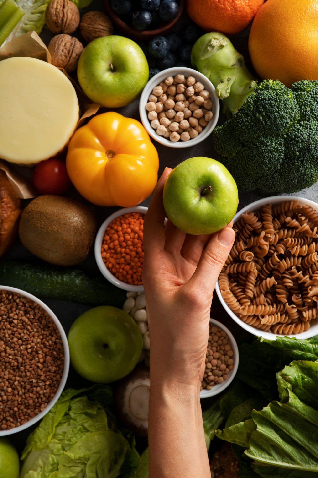 Mano sosteniendo una manzana verde entre alimentos variados